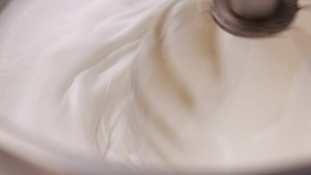 Kitchen mixer is beating the eggs white egg whites into a thick white foam. whisks whipped egg whites and sugar in the metal bowl. Whip the egg white: cook at home, make a cake, desserts, meringue
