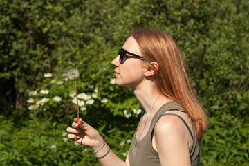 girl with red hair holding a dandelion in summer