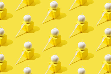 Pattern with white apple on yellow cube-shaped stand and white plastic fork.