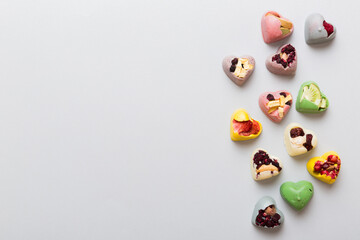 Fototapeta na wymiar chocolate sweets in the form of a heart with fruits and nuts on a colored background. top view with space for text, holiday concept