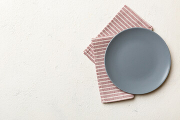 Top view on colored background empty round gray plate on tablecloth for food. Empty dish on napkin...