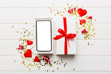 Opened gift box with ribbon and phone on color background, top view. Blank open box packaging...