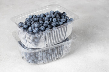 Fresh blueberries in plastic containers on a gray background, preparing berries for freezing