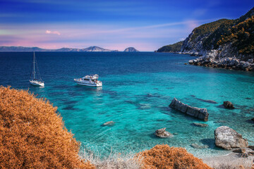 Greckie krajobrazy z wyspy Skopelos. Relaks i wypoczynek na lazurowej zatoce z żaglówkami - obrazy, fototapety, plakaty
