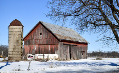 Weathered wooden barn in winter snow and blue sky