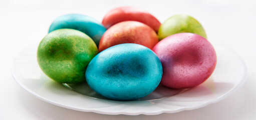 Painted multi-colored eggs on white plate