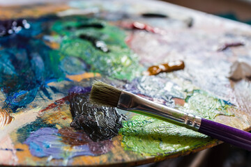 Fototapeta premium Home hobby.Drawing at home.Art school.Free time.Palette with paints.Drawing with a brush.Oil paints.Brush with paints.Palette of colors.Color mixing.Favorite hobby. Artist.Learning to draw.Colors.