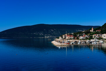 Fototapeta na wymiar beautiful view of small adriatic town Melinje, Herceg Novi in Montenegro, green coat, stone buildings, pebble beach, fishing boats, marina with yachts at berth