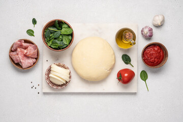 Ingredients for making pizza with ham, tomato sauce and mozzarella cheese. Top view of yeast dough and traditional italian products. Home cooking concept