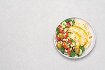 Fototapeta na wymiar Hummus salad in plate on light background with copy space. Healthy food. Dip plate appetizer with greek salad