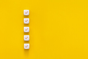 Сubes with check mark on yellow background, Checklist concept with copy space. - obrazy, fototapety, plakaty