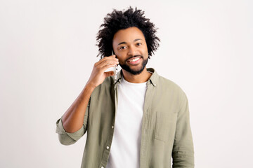Intelligent african-american male freelancer or student talking on the smartphone isolated on white, curly handsome man in casual green shirt has pleasant phone conversation