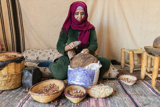 Muslim woman crushing argan nut to make cosmetic oil in cooperative