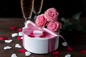 Beautiful surprise greeting for saint Valentine's or Women's Day, birthday or Anniversary for beloved. Fresh pink roses, gift box with sweets. Dark background. Holiday atmosphere
