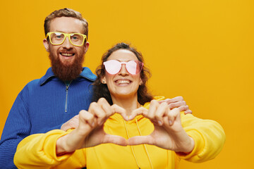 Man and woman couple smiling cheerfully and crooked with glasses, on yellow background, symbols...