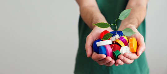 handful of colorful plastic lids with green leaves. Concept of environmental pollution and eco friendly behavior. waste sorting and plastic recycling. banner with copy space