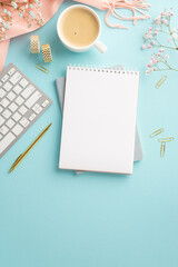 Business concept.Top view vertical photo of notepad cup of coffee keyboard golden pen clips adhesive tape gypsophila flowers and pink scarf on isolated pastel blue background with empty space