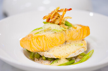 Close-up of salmon fillet with rice cakes, green beans, lemon butter garlic sauce. Seafood dish on white plate. Healthy lunch on cafe table. Food, recipe, restaurant menu background. Pescatarian diet.