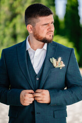 portrait of a man with a beard in a classic suit with a boutonniere outdoors.