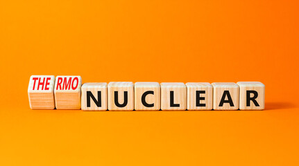 Nuclear or thermonuclear energy symbol. Concept words Nuclear or Thermonuclear on wooden cubes. Beautiful orange table orange background. Business Nuclear or thermonuclear concept. Copy space.