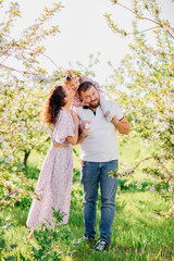 Fototapeta premium a mom and a dad with a baby daughter in a blooming spring garden. happy family. 
