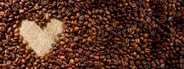 Coffee break background. Hot coffee in cup and roasted coffee beans on a wooden table. Copy space