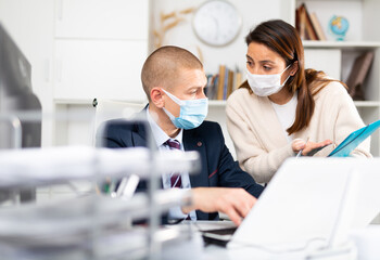 Business coworkers man and woman in protective fase masks discussing new ideas and brainstorming in modern office