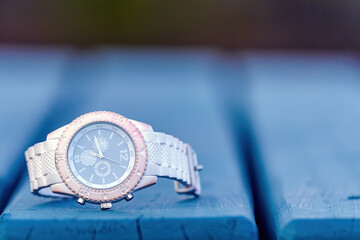 A lost pink watch on a picnic table. Closeup view. Branding removed.