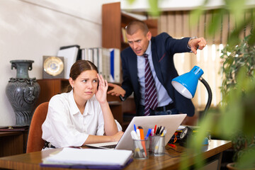 Dissatisfied manager scolding frustrated female assistant in office