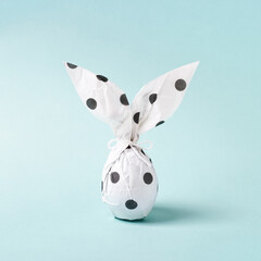 Easter bunny in wrapping paper. DIY gift concept. Easter egg as white rabbit. Easter greeting card, minimal style.