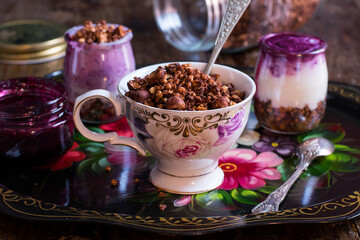 Bandeja vintage con vasitos de yogur con granola y mermelada de arándanos, taza bonita llena de granola