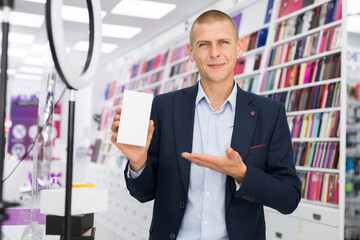 An electronics store seller demonstrates box with a mobile phone