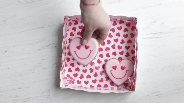 Women's hands put in box smiling gingerbread in shape of smiling hearts wonderful gift for Valentine's Day