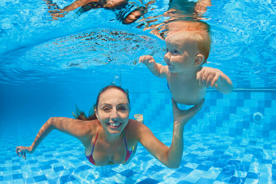 Happy people dive underwater with fun. Funny photo of mother, child in aqua park swimming pool. Family lifestyle, kids water sports activity, swimming lesson with parents on summer holiday