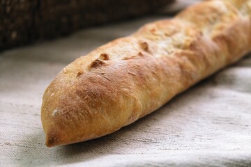 freshly baked baguette. bread on the tablecloth. Home baked whole grain bread. Crusty sourdough loaf of wheat bread with wholegrain flour. fried bread crust.