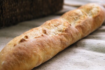 freshly baked baguette. bread on the tablecloth. Home baked whole grain bread. Crusty sourdough loaf of wheat bread with wholegrain flour. fried bread crust.