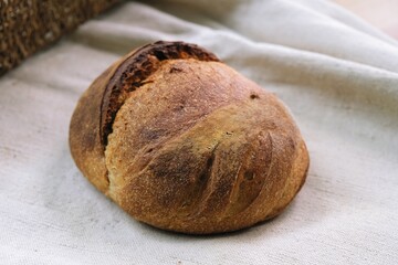 bread on the tablecloth. Home baked whole grain bread. Crusty sourdough loaf of wheat bread with wholegrain flour. fried bread crust.