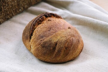 bread on the tablecloth. Home baked whole grain bread. Crusty sourdough loaf of wheat bread with wholegrain flour. fried bread crust.