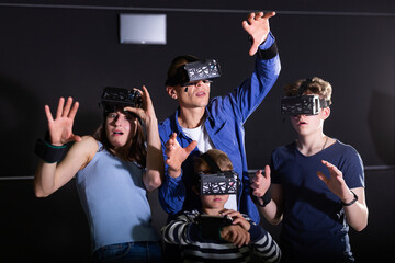 Emotional young parents with two teenage sons having fun with vr headset goggles. Concept of new...