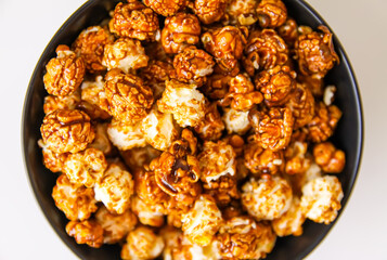 Sweet ready-to-eat popcorn in a black ceramic plate close up.