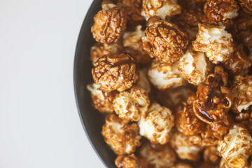Sweet ready-to-eat popcorn in a black ceramic plate close up.