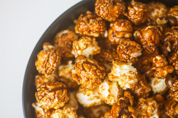 Sweet ready-to-eat popcorn in a black ceramic plate close up.