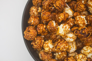 Sweet ready-to-eat popcorn in a black ceramic plate close up.