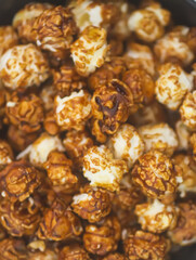 Sweet ready-to-eat popcorn in a black ceramic plate close up.