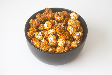 Sweet ready-to-eat popcorn in a black ceramic plate close up.