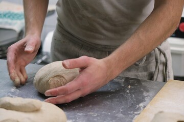 Fototapeta premium baker at work. The baker shapes the bread. Hands on the close-up form bread