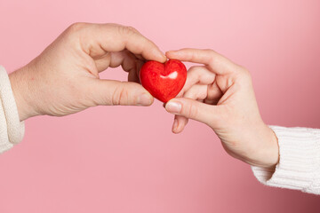 Fototapeta premium closeup hands holding heart on pink background, valentine's day concept
