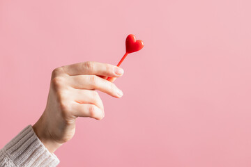 closeup hands holding heart on pink background, valentine's day concept