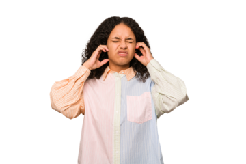 Young african american curly woman isolated covering ears with fingers, stressed and desperate by a loudly ambient.