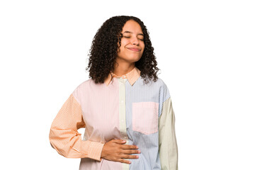 Fototapeta premium Young african american curly woman isolated touches tummy, smiles gently, eating and satisfaction concept.